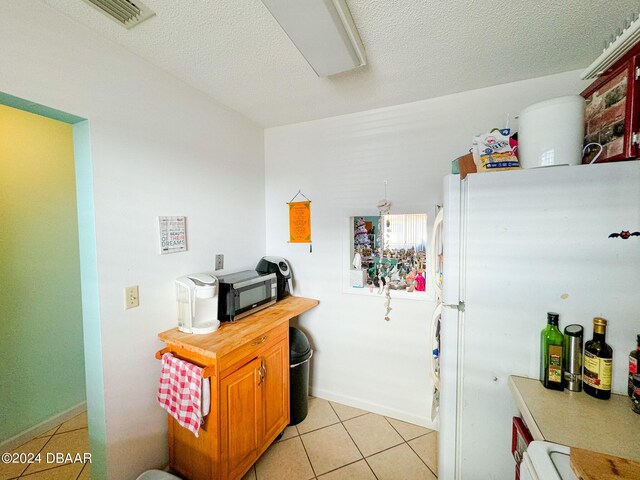 2801 N Halifax Ave Unit 250, Daytona Beach, FL 32118 - kitchen with freestanding refrigerator, stainless steel microwave, light tile patterned flooring, a textured ceiling, and butcher block counters