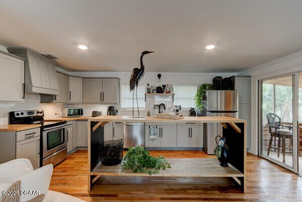 kitchen featuring appliances with stainless steel finishes, light hardwood / wood-style floors, custom range hood, and gray cabinetry