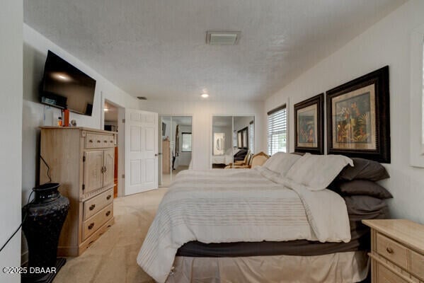 bedroom featuring light carpet and a textured ceiling