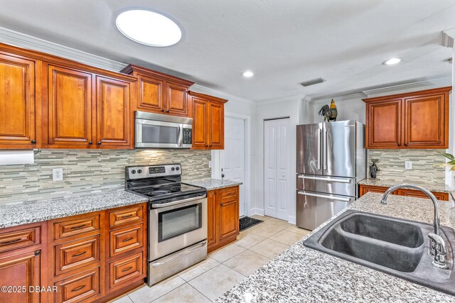 887 Sugar House Ct, Port Orange, FL 32129 - kitchen featuring stainless steel appliances, light tile patterned floors, ornamental molding, decorative backsplash, and brown cabinets