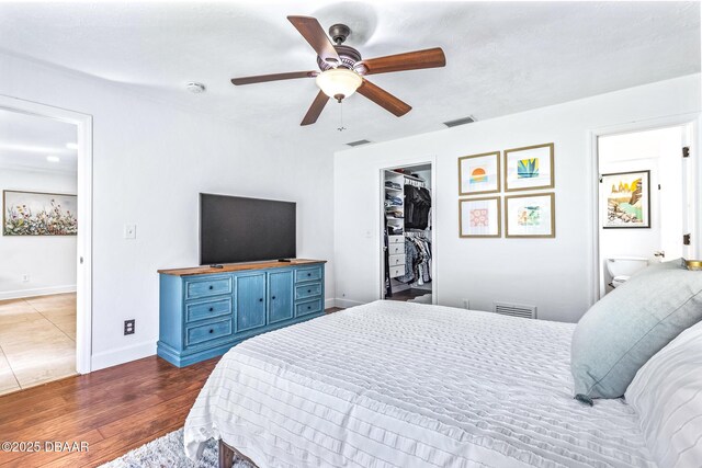 887 Sugar House Ct, Port Orange, FL 32129 - bedroom featuring a walk in closet, a ceiling fan, wood finished floors, and ensuite bath