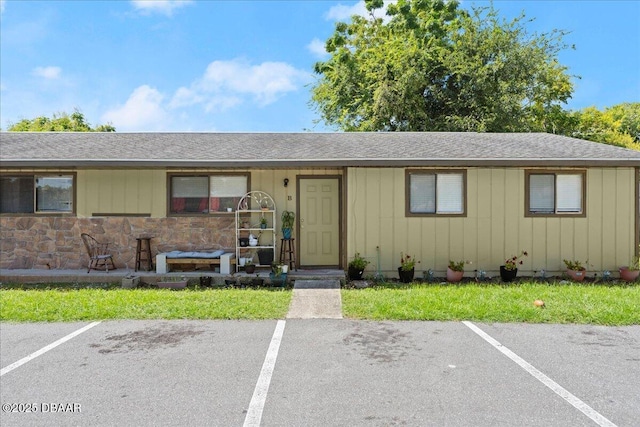 ranch-style house featuring uncovered parking, a shingled roof, and a front lawn