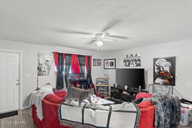 living area with ceiling fan, a textured ceiling, and wood finished floors