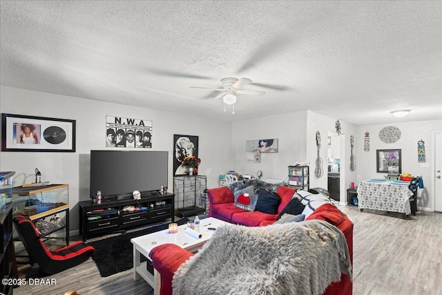 living room featuring ceiling fan, a textured ceiling, and wood finished floors