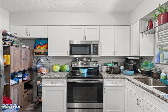 kitchen with stainless steel appliances, white cabinetry, and a textured ceiling