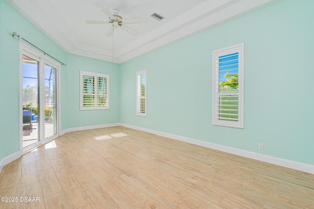 spare room with plenty of natural light, a ceiling fan, a raised ceiling, and light wood-style floors