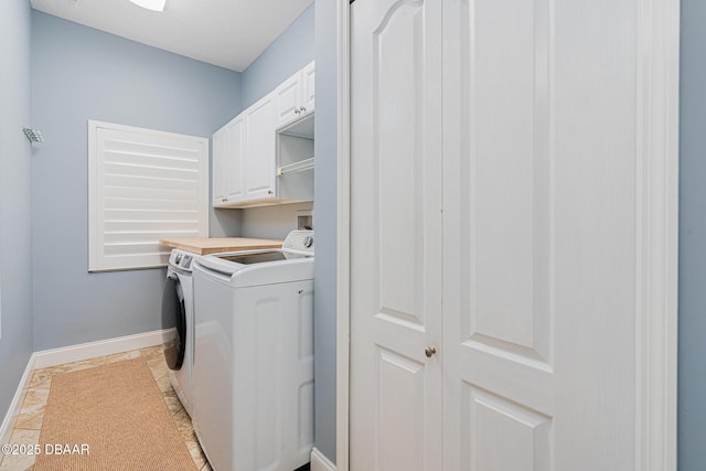 clothes washing area with baseboards, cabinet space, and independent washer and dryer