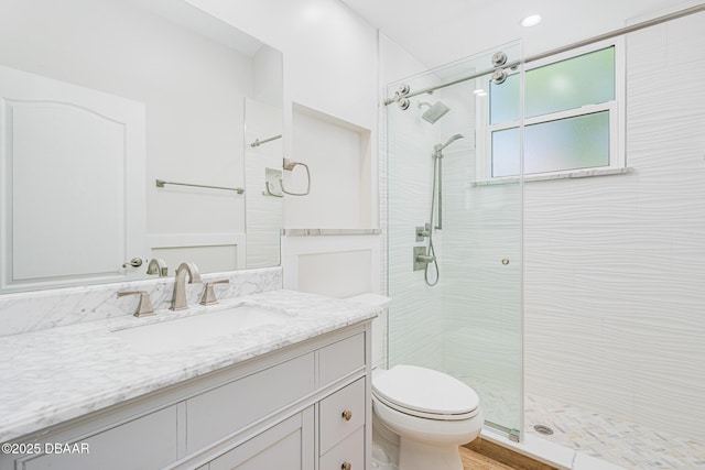 bathroom featuring toilet, a shower stall, and vanity