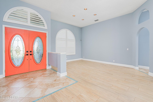 foyer featuring baseboards, arched walkways, light wood-type flooring, recessed lighting, and french doors