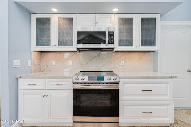 kitchen with backsplash, light stone counters, stainless steel appliances, and white cabinetry