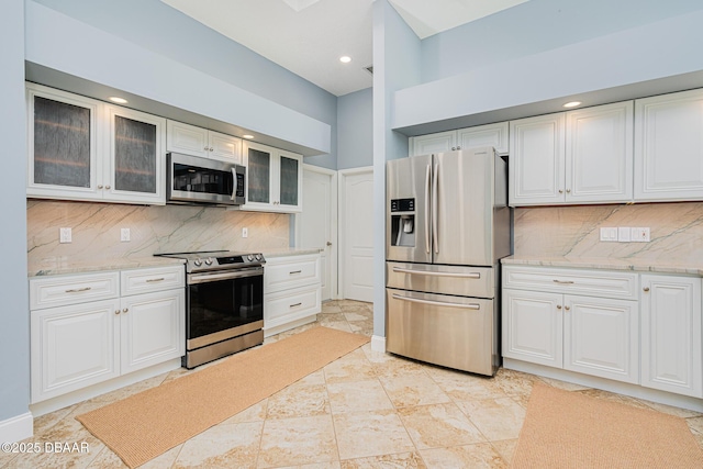 kitchen with stainless steel appliances, white cabinets, and backsplash