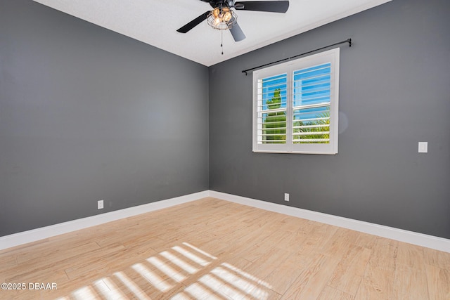 unfurnished room featuring a ceiling fan, wood finished floors, and baseboards