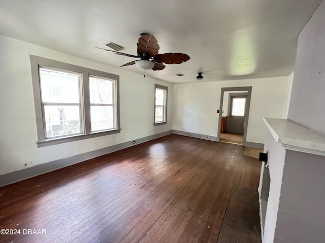 unfurnished living room featuring ceiling fan, dark wood-type flooring, and a healthy amount of sunlight