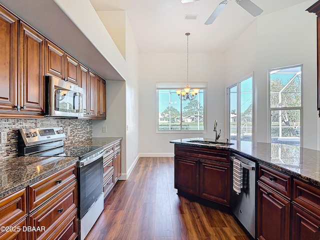 kitchen featuring sink, stainless steel appliances, dark hardwood / wood-style floors, tasteful backsplash, and dark stone counters