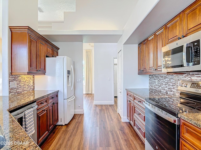 kitchen with appliances with stainless steel finishes, dark hardwood / wood-style floors, beverage cooler, decorative backsplash, and dark stone counters