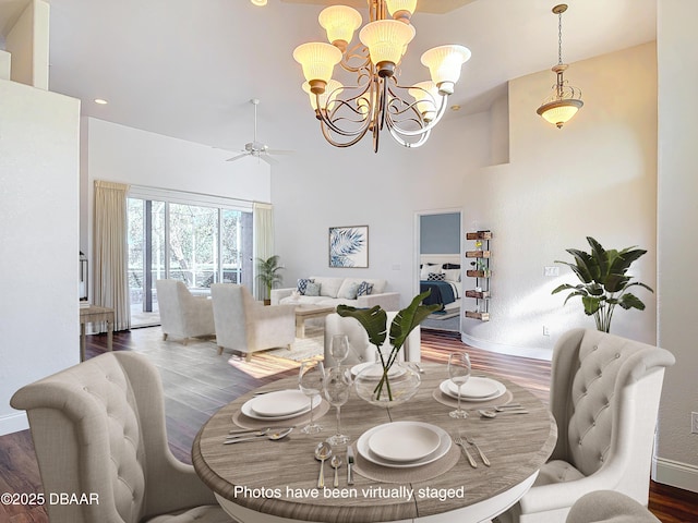 dining room with a towering ceiling, dark hardwood / wood-style floors, and ceiling fan with notable chandelier