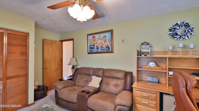living room with visible vents, a ceiling fan, carpet, and a textured ceiling