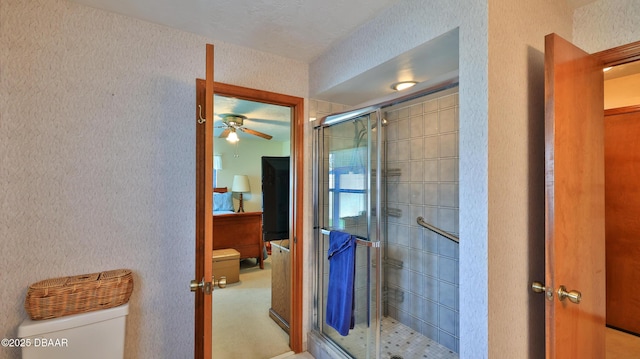 ensuite bathroom with ensuite bathroom, a ceiling fan, a stall shower, and toilet