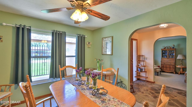 dining space with arched walkways and ceiling fan