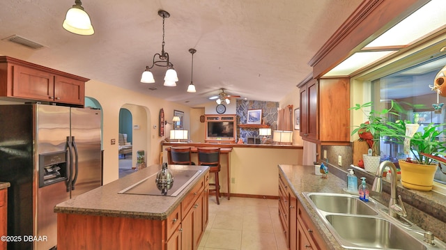 kitchen featuring visible vents, a sink, black electric stovetop, stainless steel refrigerator with ice dispenser, and arched walkways