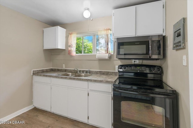 2300 Calloway Dr, Orlando, FL 32810 - kitchen with black electric range oven, stainless steel microwave, light wood-style flooring, and white cabinets