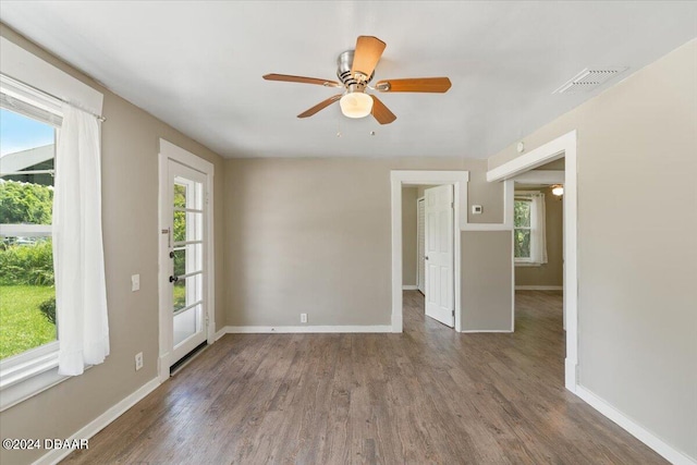 unfurnished room with ceiling fan, a wealth of natural light, and dark hardwood / wood-style floors