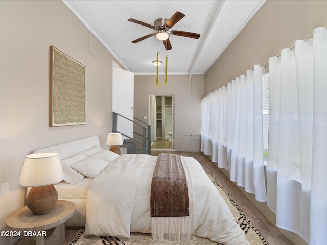 bedroom featuring wood-type flooring, a textured ceiling, connected bathroom, ornamental molding, and ceiling fan