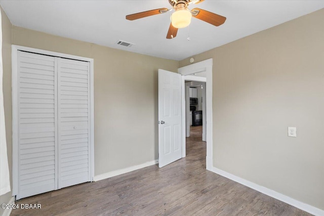 unfurnished bedroom featuring hardwood / wood-style floors, ceiling fan, and a closet