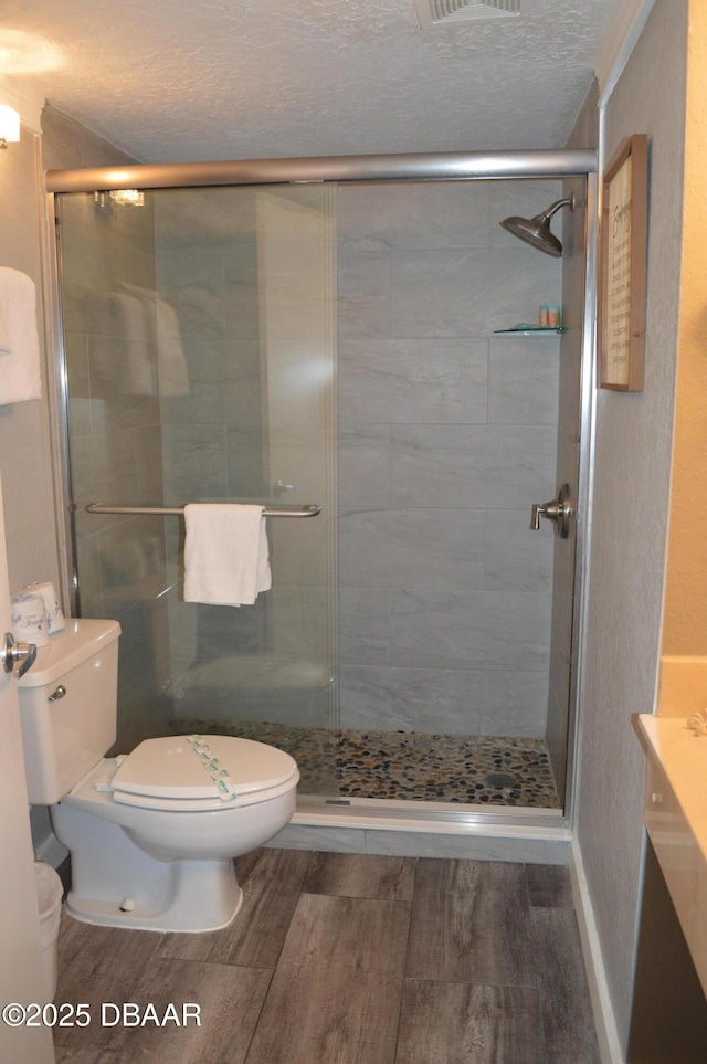 bathroom with vanity, a textured ceiling, toilet, and walk in shower