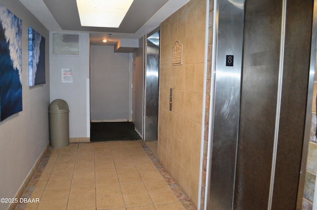 corridor featuring light tile patterned flooring and elevator