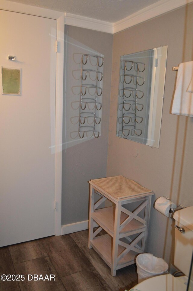 bathroom featuring wood-type flooring, ornamental molding, and toilet