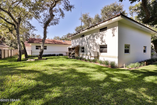 back of house featuring fence, a lawn, and stucco siding