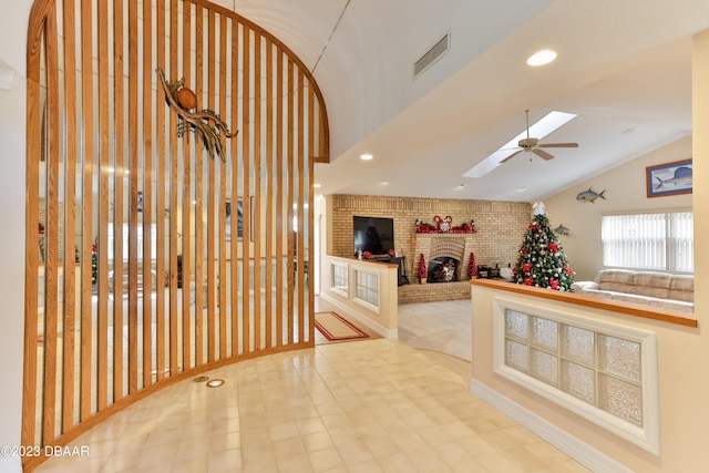 unfurnished living room featuring a fireplace, recessed lighting, visible vents, a ceiling fan, and vaulted ceiling with skylight