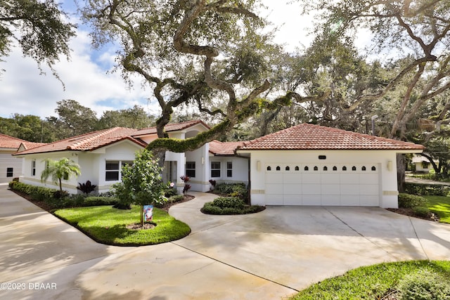 mediterranean / spanish-style home featuring a garage, a tile roof, and stucco siding