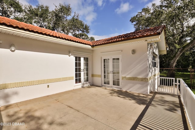 back of property with stucco siding, a tiled roof, a patio area, and french doors