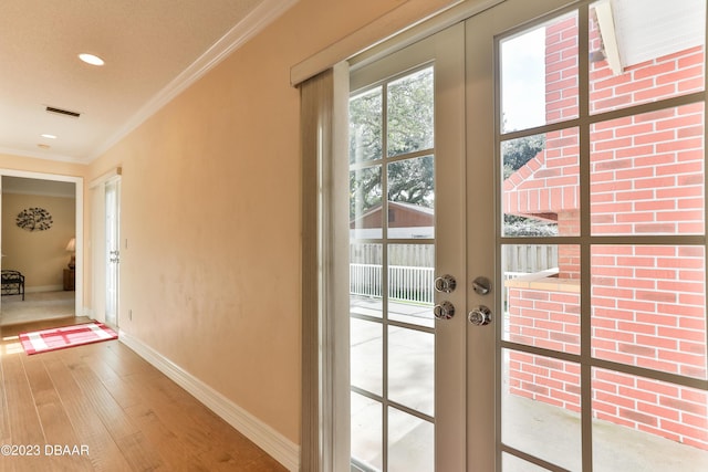 doorway to outside with wood finished floors, visible vents, baseboards, french doors, and ornamental molding