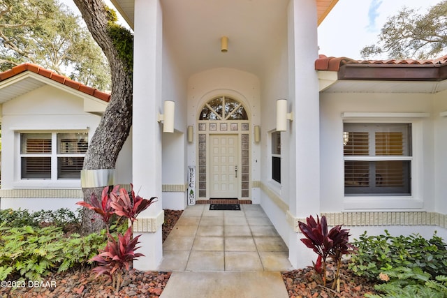 property entrance featuring a tile roof and stucco siding