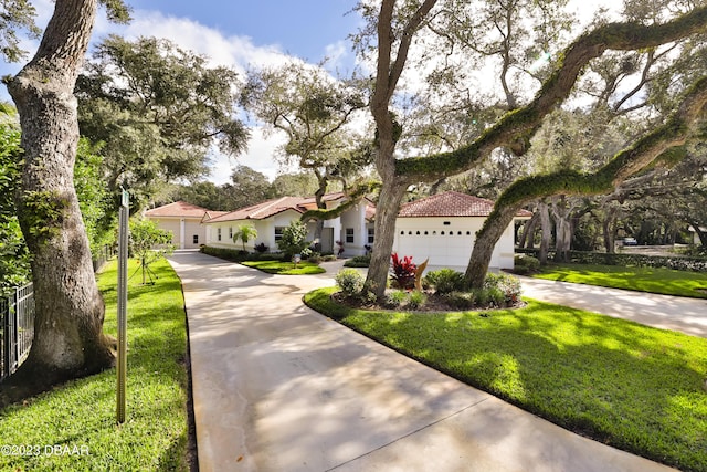 mediterranean / spanish house featuring a front yard, concrete driveway, a tile roof, and stucco siding