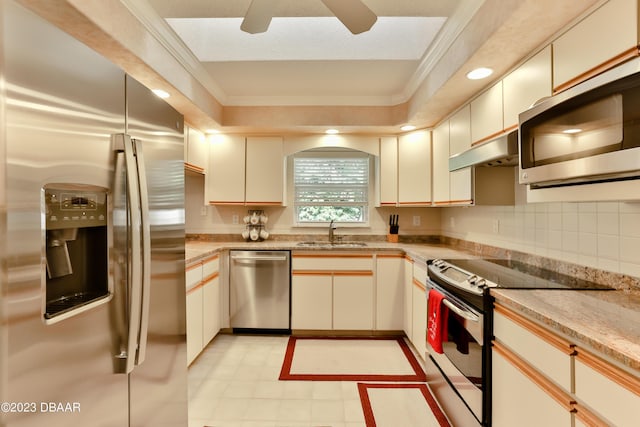 kitchen featuring stainless steel appliances, crown molding, a sink, and under cabinet range hood