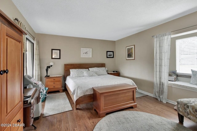 bedroom with a textured ceiling and light hardwood / wood-style flooring