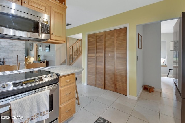 kitchen with light tile patterned floors, stainless steel appliances, and light brown cabinetry