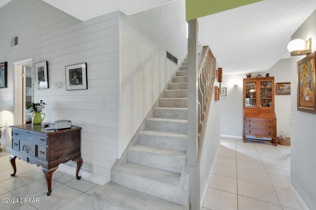 stairs with tile patterned floors, a textured ceiling, and lofted ceiling