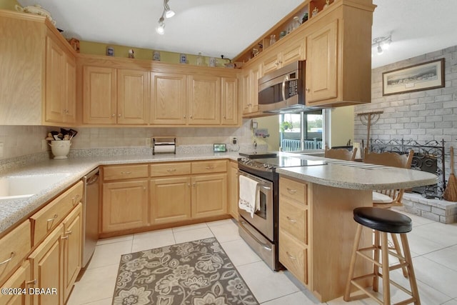 kitchen featuring a kitchen breakfast bar, light brown cabinetry, light tile patterned flooring, kitchen peninsula, and stainless steel appliances