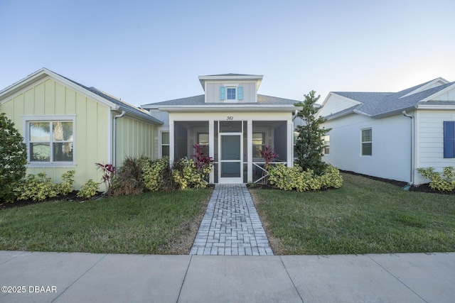 view of front of house featuring a sunroom and a front yard