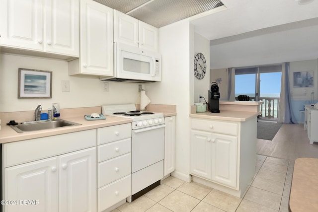 kitchen with sink, white appliances, light tile patterned floors, white cabinetry, and kitchen peninsula