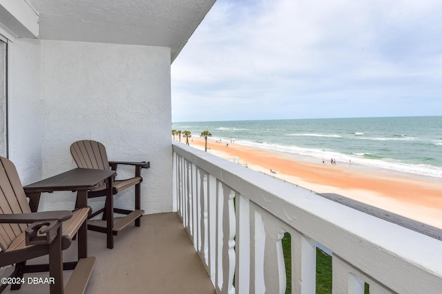 balcony with a water view and a view of the beach