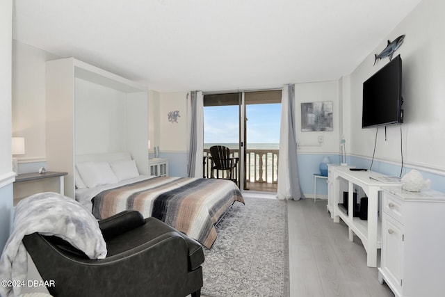 bedroom featuring access to exterior, light hardwood / wood-style floors, and a wall of windows