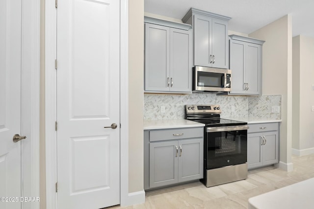 1372 Lombardi Ct, Poinciana, FL 34759 - kitchen featuring gray cabinetry, backsplash, and appliances with stainless steel finishes