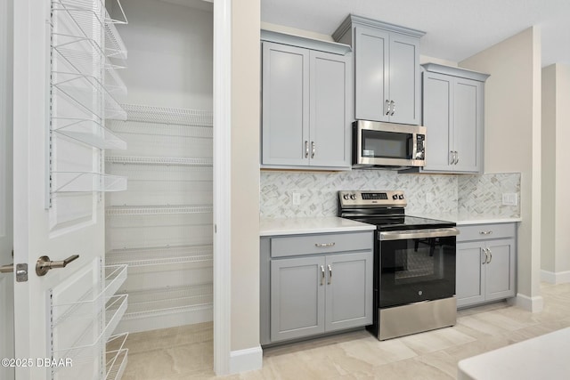 1372 Lombardi Ct, Poinciana, FL 34759 - kitchen with stainless steel appliances, gray cabinetry, and backsplash