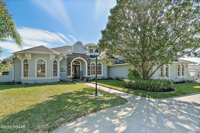 mediterranean / spanish home featuring stone siding, a front lawn, and stucco siding